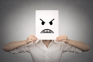 businesswoman covering her face with angry mask isolated grey wall background. Negative emotions, feelings, expressions, body language